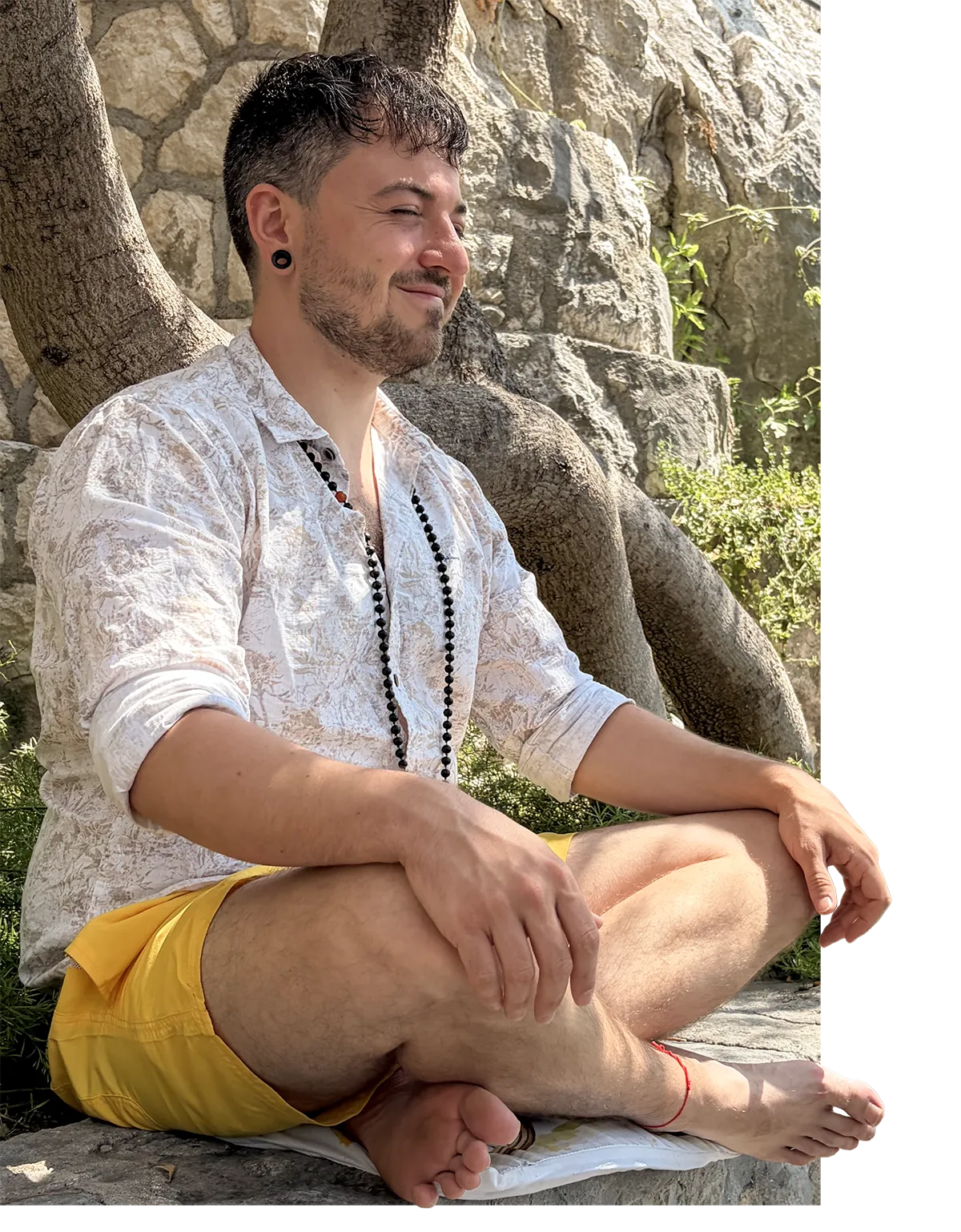 Enrico Fricke sitzt im Sonnenlicht vor einer Steinmauer.